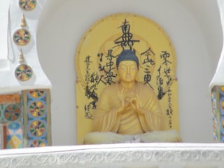The golden Buddha at the centre of the stupa depicts the “Turning Wheel of Dharma”.