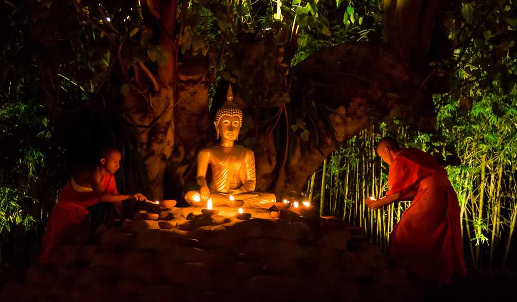 Monks lighting candles at Wat Phan Tao on Makha Bucha Day