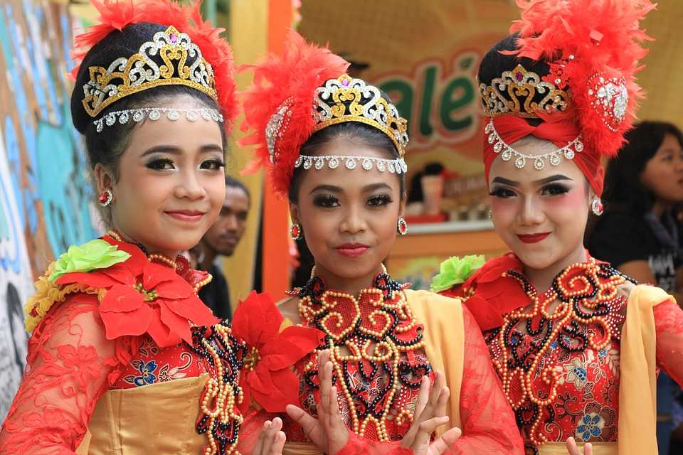  Three young female dancers in traditional Indonesian folk costumes perform a traditional dance with modern technology.